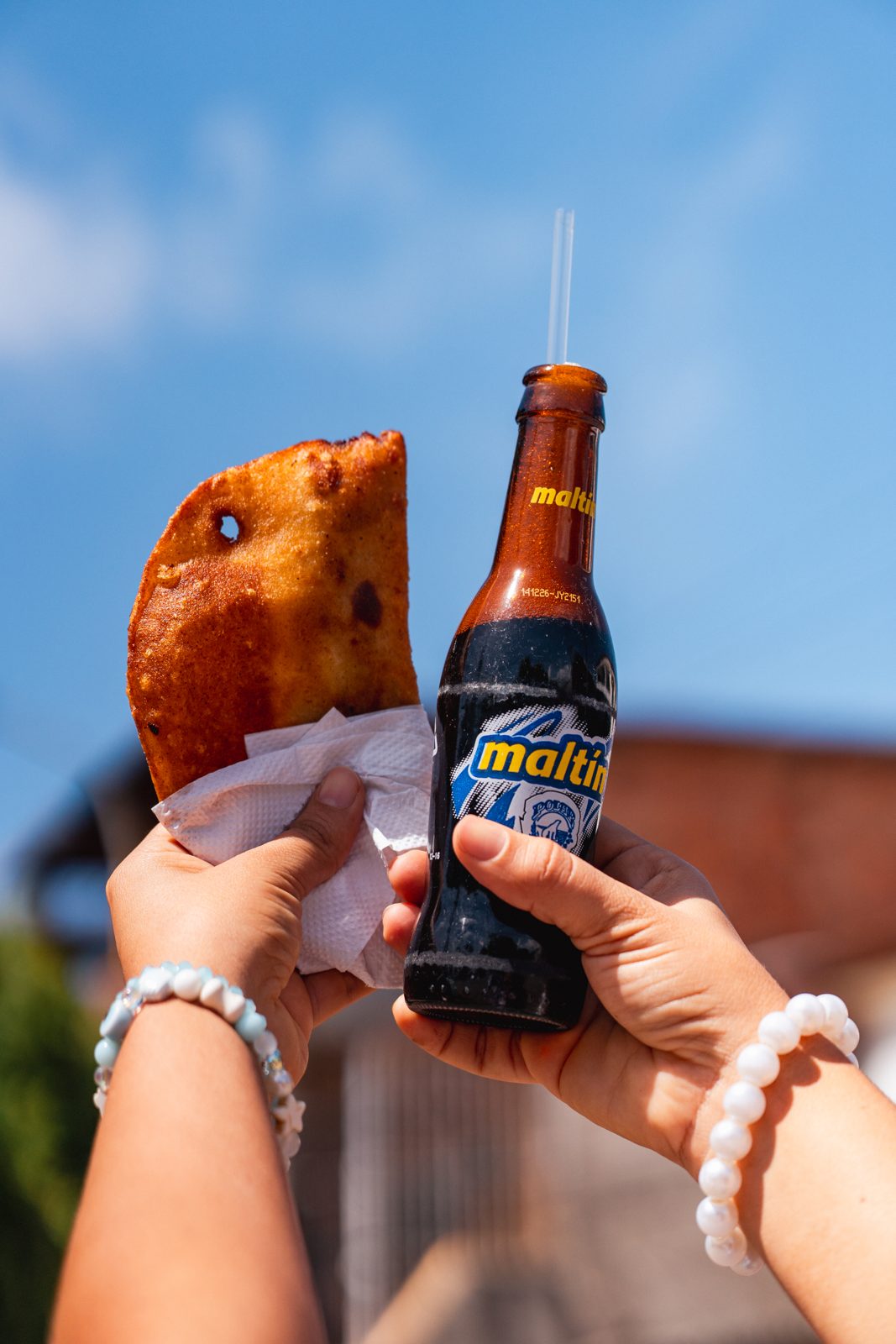 Empanada y malta en la mano